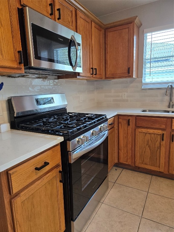 kitchen with stainless steel appliances, light tile patterned flooring, decorative backsplash, and sink