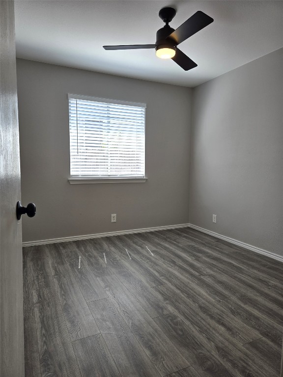 unfurnished room with ceiling fan and dark wood-type flooring