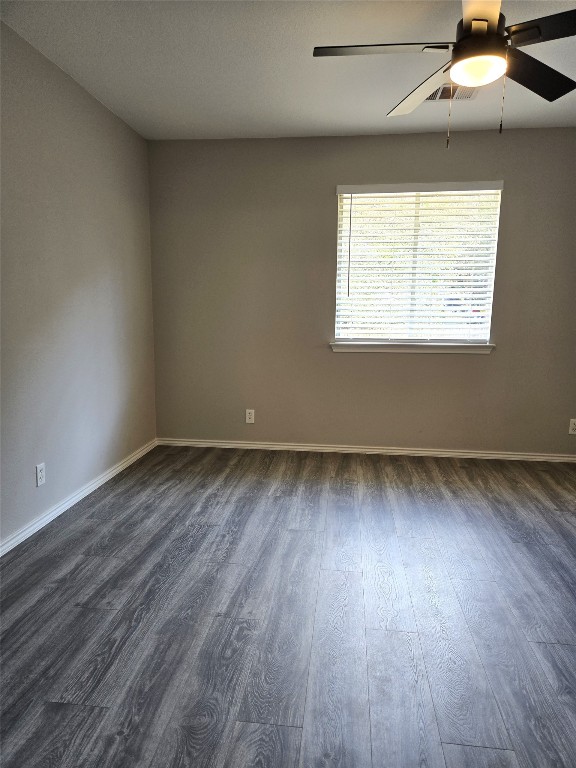 empty room with ceiling fan and dark hardwood / wood-style floors