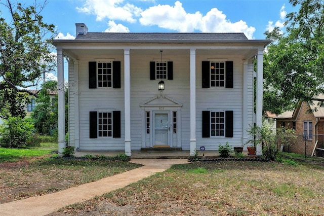 neoclassical / greek revival house featuring a front yard and a porch