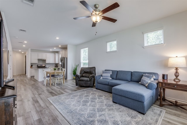 living room with ceiling fan, light wood-type flooring, and a wealth of natural light