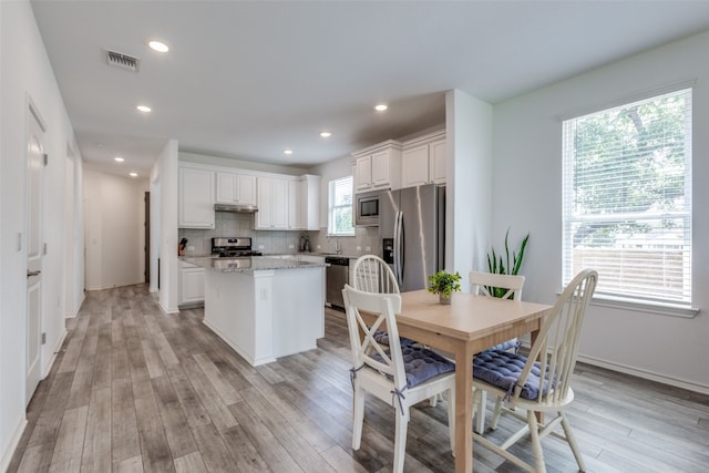 kitchen featuring white cabinetry, a center island, stainless steel appliances, and a wealth of natural light