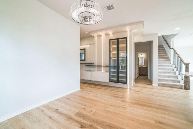 unfurnished living room with light hardwood / wood-style flooring and a notable chandelier