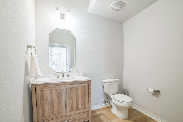 bathroom featuring wood-type flooring, vanity, and toilet