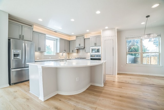 kitchen with light hardwood / wood-style flooring, stainless steel appliances, and tasteful backsplash