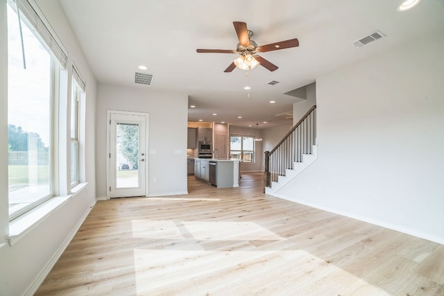 unfurnished living room with ceiling fan and light hardwood / wood-style flooring