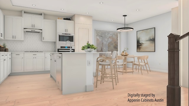 kitchen featuring white cabinets, a kitchen island, decorative light fixtures, and light hardwood / wood-style flooring