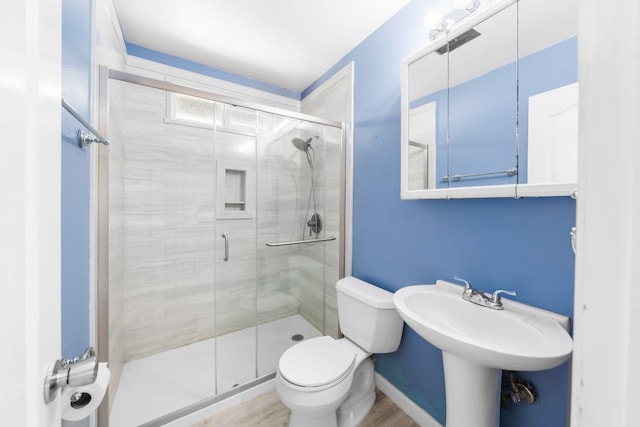 bathroom with hardwood / wood-style floors, a shower with door, and toilet