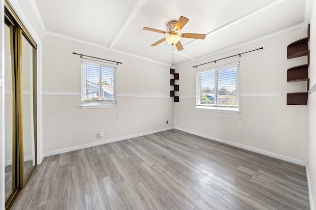 unfurnished bedroom with crown molding, a closet, multiple windows, and light wood-type flooring