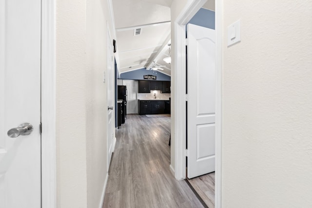 corridor featuring wood-type flooring and vaulted ceiling with beams