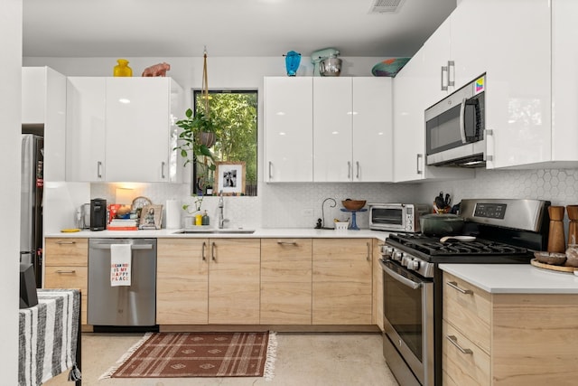 1001 Juanita St, Austin, TX 78704 - kitchen featuring stainless steel appliances, light countertops, decorative backsplash, and white cabinets