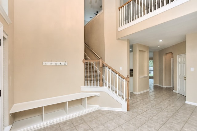 stairway featuring a towering ceiling and tile patterned floors