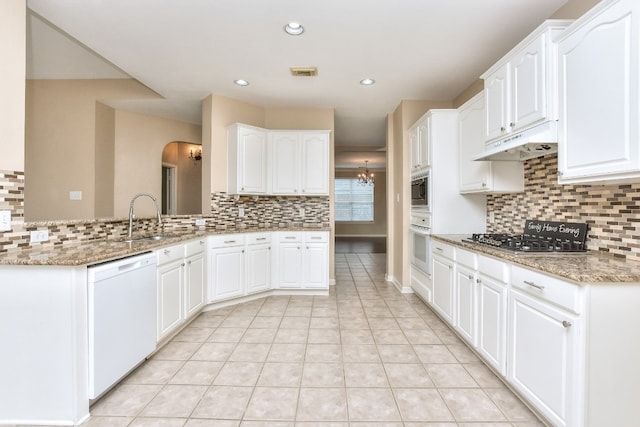 kitchen featuring light stone counters, white cabinets, sink, kitchen peninsula, and white appliances