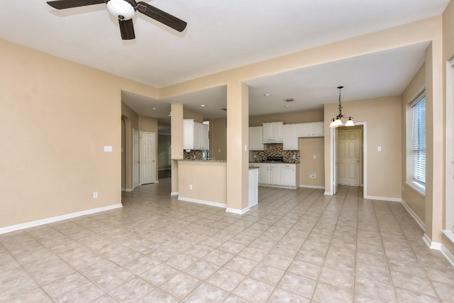 unfurnished living room with ceiling fan with notable chandelier