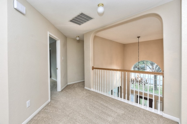 hallway with carpet and a notable chandelier