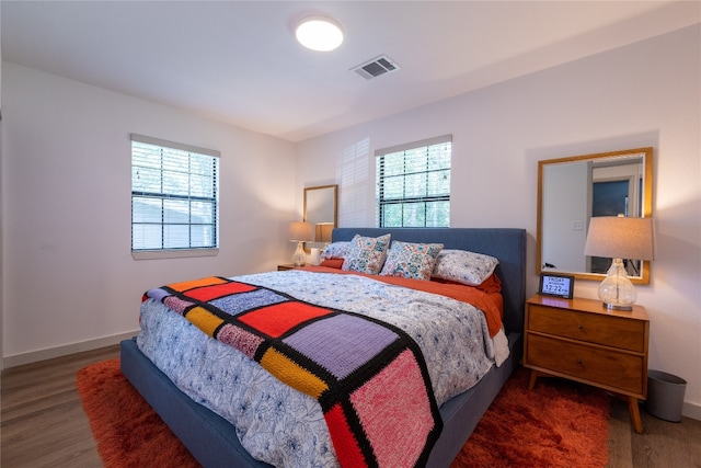 bedroom with multiple windows and dark hardwood / wood-style floors