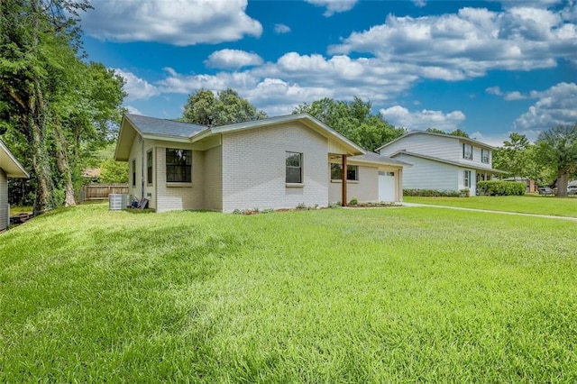 view of front of property featuring a front yard, cooling unit, and a garage