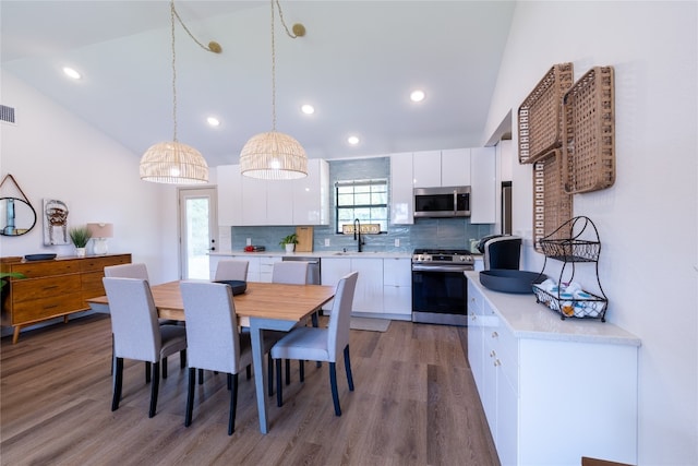 dining room featuring wood-type flooring, lofted ceiling, sink, and a healthy amount of sunlight