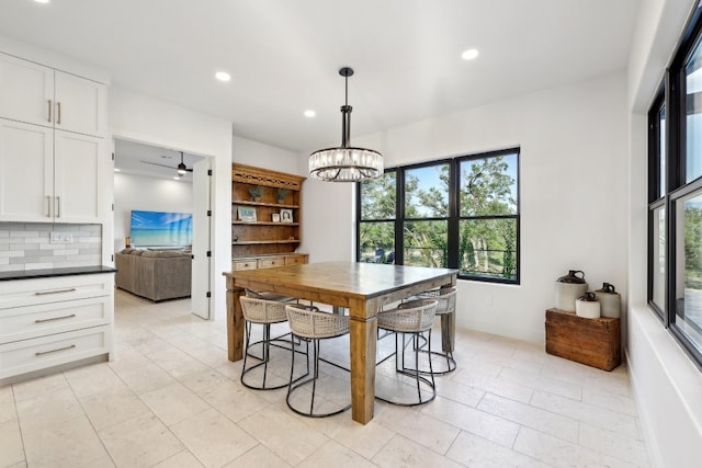 tiled dining area featuring ceiling fan with notable chandelier