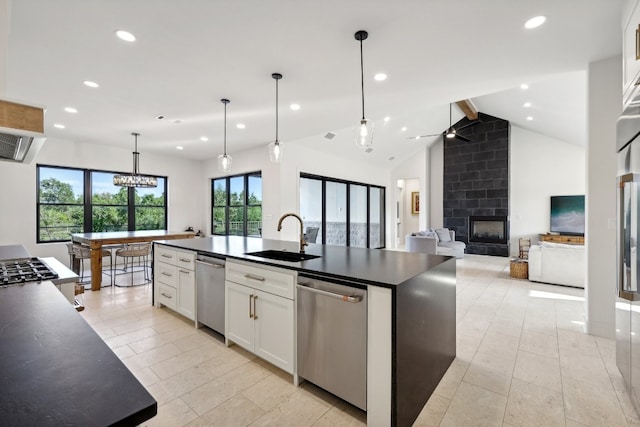 kitchen with a kitchen island with sink, sink, a large fireplace, and stainless steel dishwasher