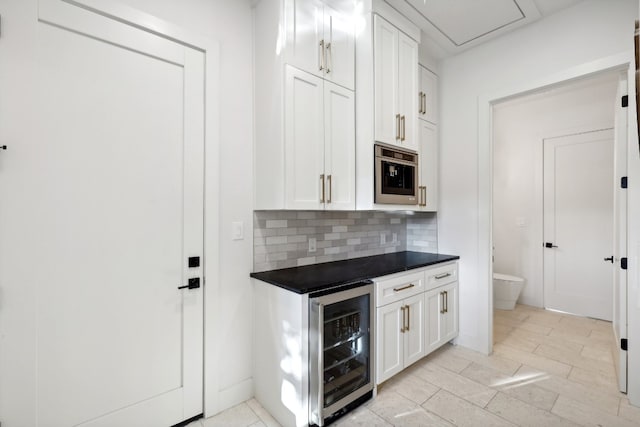 kitchen featuring beverage cooler, backsplash, light tile patterned flooring, and white cabinetry