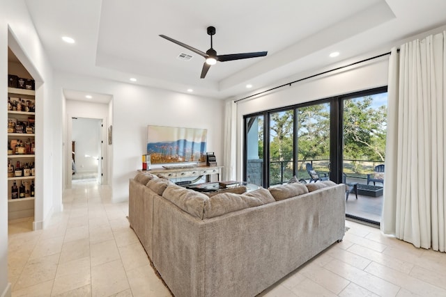 living room with a tray ceiling and ceiling fan