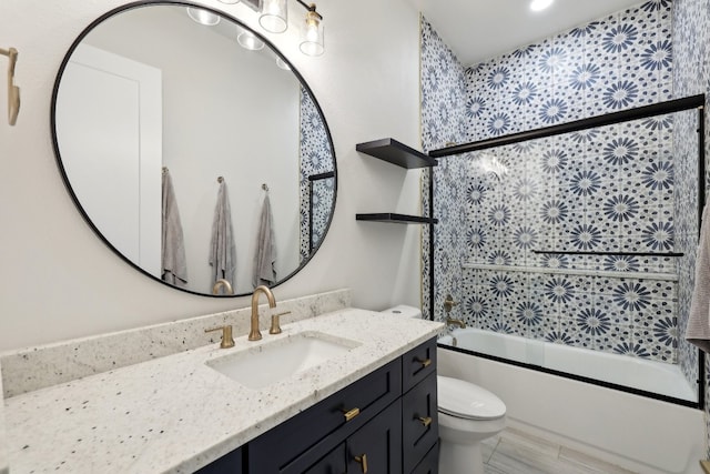 full bathroom featuring enclosed tub / shower combo, vanity, and toilet