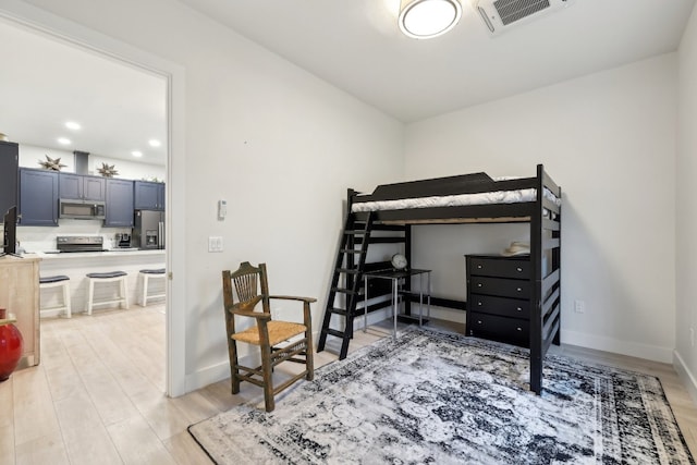 bedroom with light hardwood / wood-style flooring and stainless steel fridge with ice dispenser