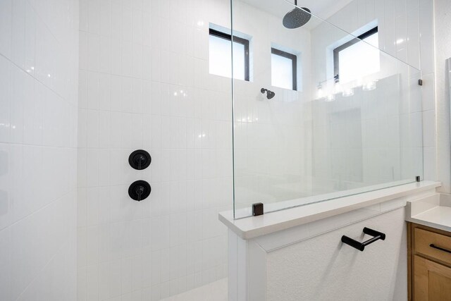 bathroom featuring a tile shower and vanity