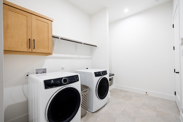 clothes washing area with separate washer and dryer, light tile patterned floors, and cabinets