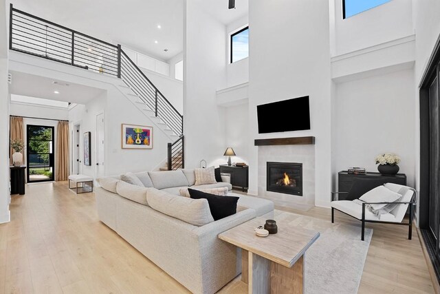 living room with light hardwood / wood-style floors, a towering ceiling, and a tile fireplace