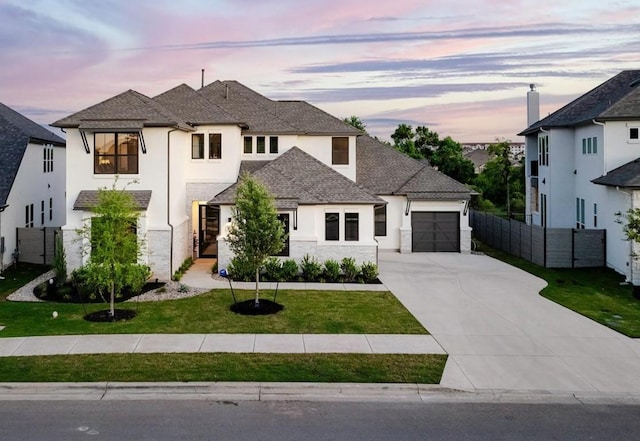 view of front of property featuring concrete driveway, an attached garage, fence, a front yard, and stucco siding