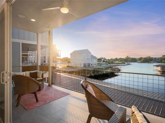 balcony at dusk featuring a water view