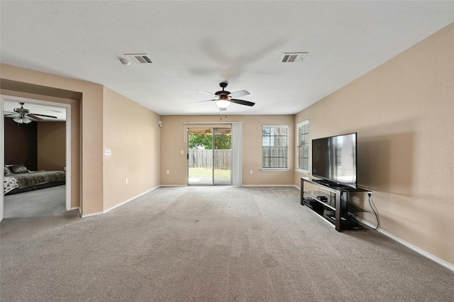 unfurnished living room featuring a textured ceiling, carpet, and ceiling fan