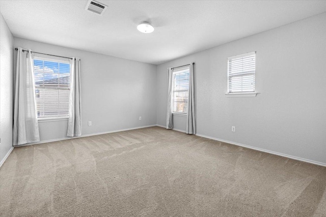 unfurnished room with carpet floors, visible vents, and plenty of natural light