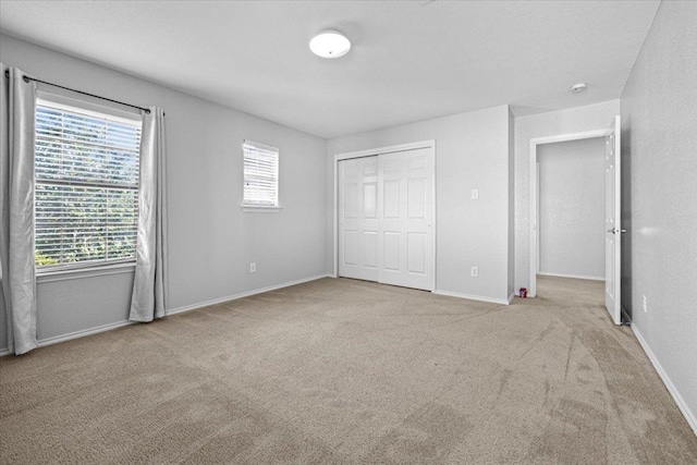 unfurnished bedroom featuring a closet, light carpet, and multiple windows