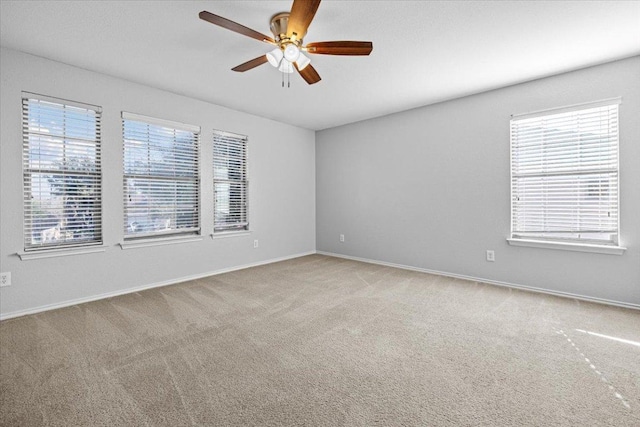 carpeted spare room with ceiling fan and baseboards