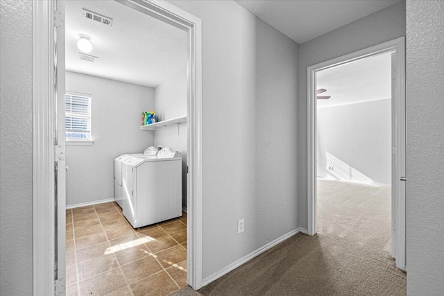 clothes washing area featuring light carpet, laundry area, visible vents, baseboards, and washer / clothes dryer