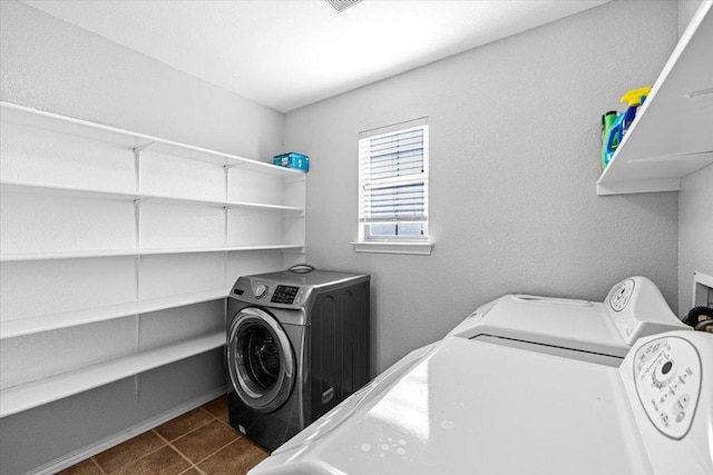 laundry room with washing machine and dryer, laundry area, and dark tile patterned floors