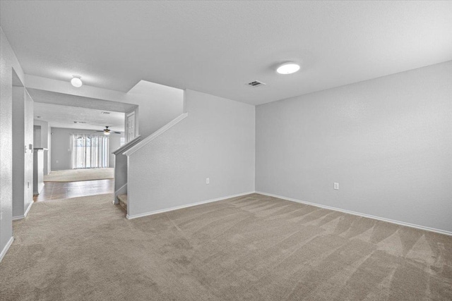 carpeted spare room with visible vents, stairway, and baseboards