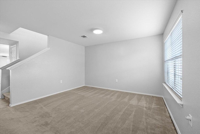 empty room featuring carpet, visible vents, stairway, and baseboards