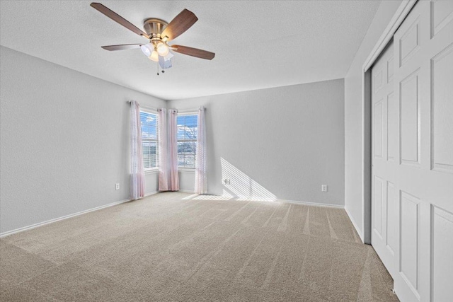 unfurnished bedroom with carpet floors, a closet, a textured ceiling, and baseboards