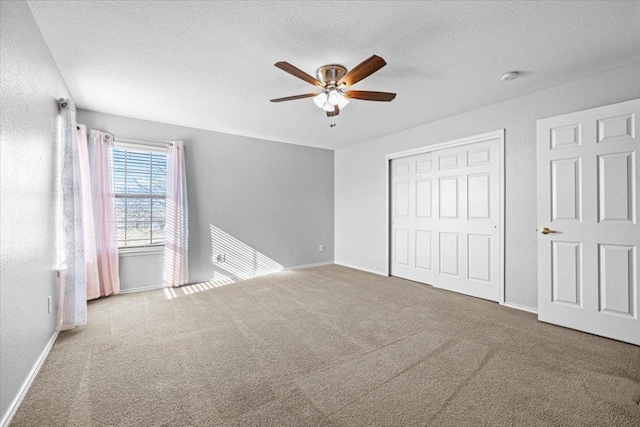 unfurnished bedroom featuring a textured ceiling, ceiling fan, carpet floors, baseboards, and a closet