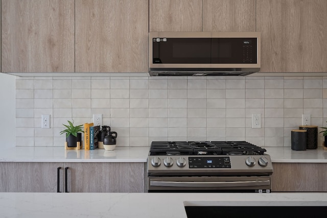 kitchen featuring decorative backsplash, light brown cabinets, and stainless steel appliances