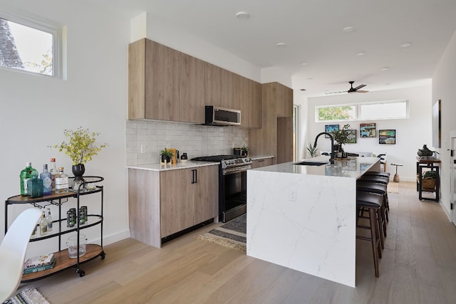 kitchen featuring appliances with stainless steel finishes, a center island with sink, plenty of natural light, and sink