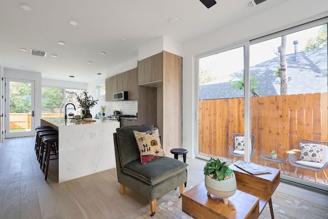 kitchen with a breakfast bar, sink, a healthy amount of sunlight, and light wood-type flooring