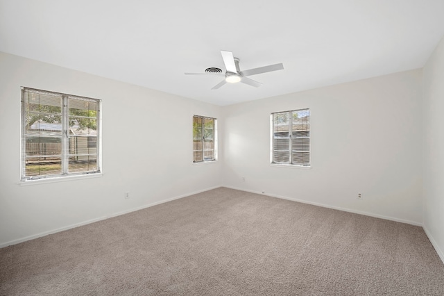 carpeted empty room featuring ceiling fan and a wealth of natural light