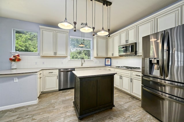 kitchen with appliances with stainless steel finishes, hanging light fixtures, decorative backsplash, and a center island