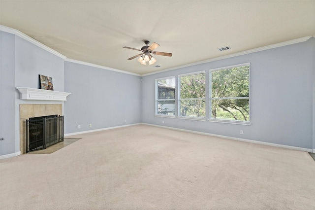 unfurnished living room with ceiling fan, light colored carpet, a tiled fireplace, and crown molding