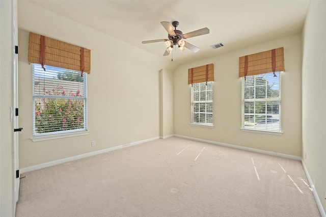 spare room featuring light carpet, ceiling fan, and a healthy amount of sunlight